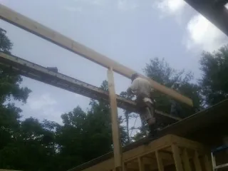Carpenter setting a ridge beam over a new addition frame — Ice Dam Removal by Roofing Brothers in Woodford