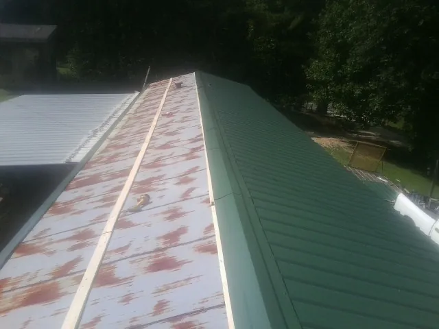 Old rusted panels beside newly installed green metal roofing — Wind Damage Roof Repair by Roofing Brothers in Woodford