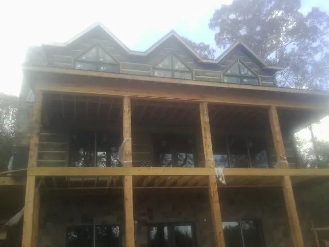 Dormers and porch framing on a large log home under construction — Roof Coating work by our crew in Woodford