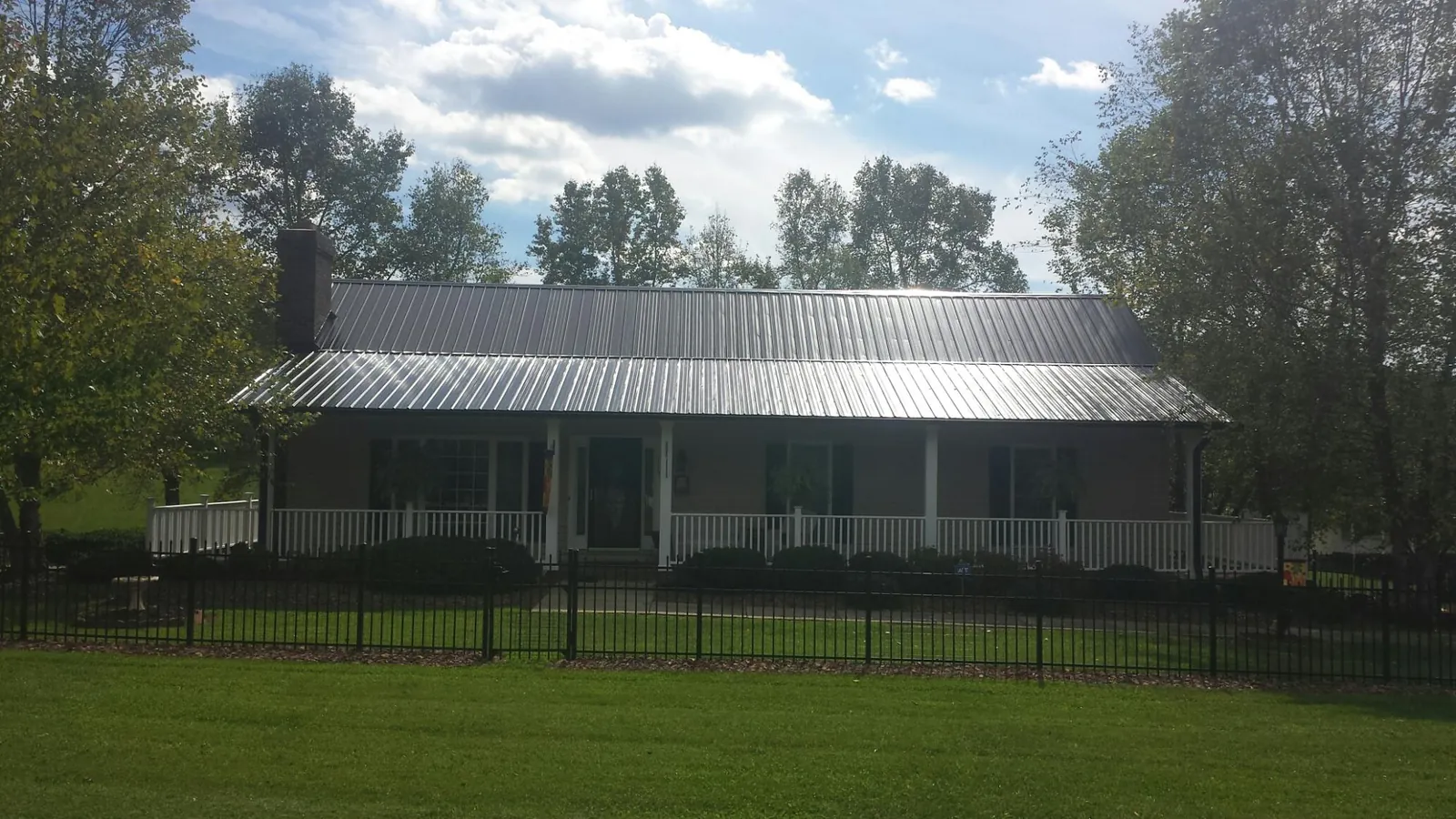 Gray metal roof on a brick ranch with a full width front porch — Gutter Guard Installation work by our crew in Woodford