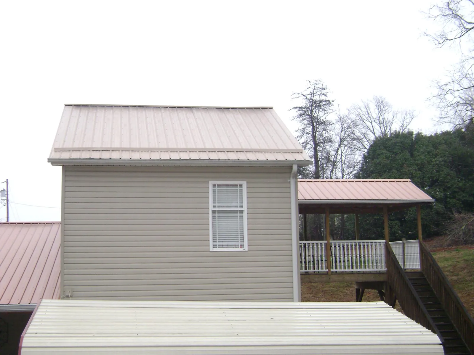 Tan metal roofs on a two story addition and attached porch, from a Roof Replacement job in Woodford