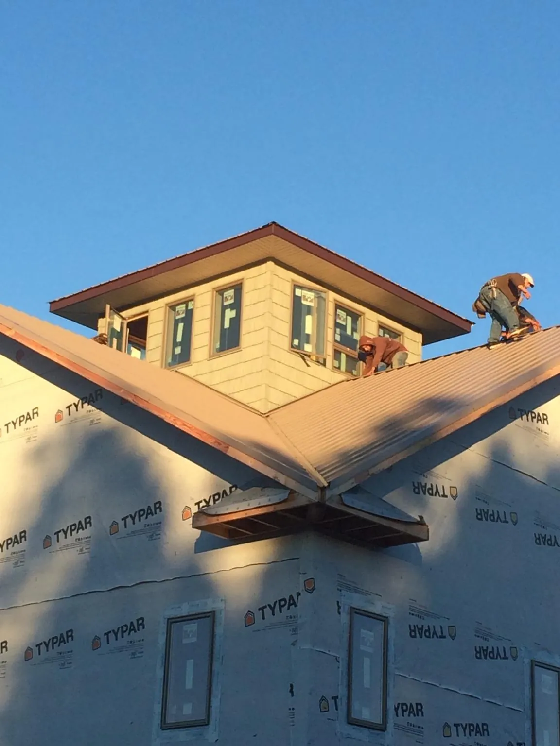 Roofers working around a rooftop cupola on a new metal roof at sunset — Roof Waterproofing in Woodford by Roofing Brothers